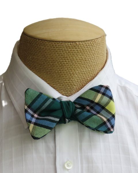 Green and yellow plaid freestyle bow tie on a mannequin with a white shirt