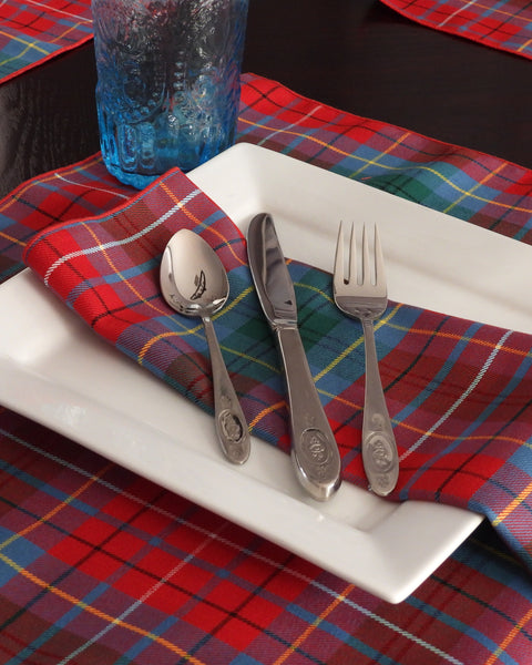 Silverware on a BC tartan napkins on white plate with a red and blue plaid tablecloth