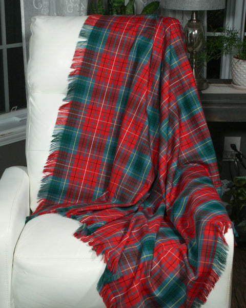 Red and green British Columbia plaid blanket draped over a white chair with a blurred indoor background.