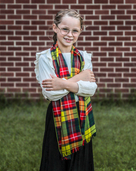 Young girl wearing a Beuchanan tartan scarf in front of a brick wall