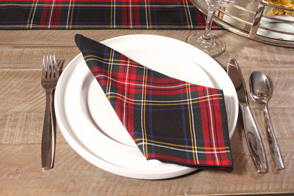 Close-up of a black and red Black Stewart tartan napkin on a white plate, next to a matching table runner.