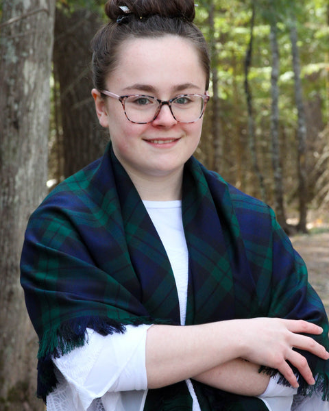 Person wearing a green plaid shawl in a forest setting