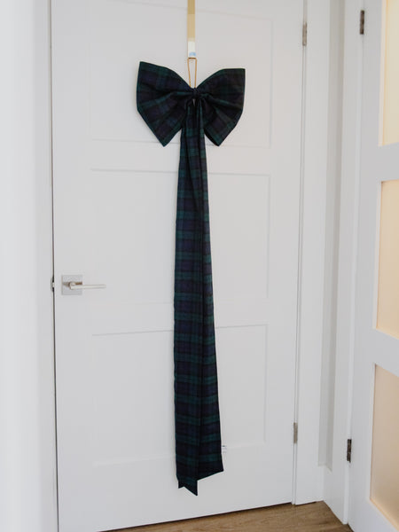 A Black Watch tartan black and green plaid over size bow on the front of a white door