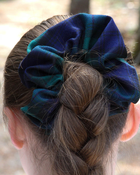 Blue scrunchie on a braided hairstyle with a blurred natural background