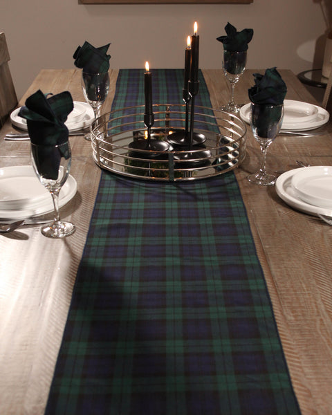 Dining table set with a Black Watfh plaid tartan runner, candles, and glasses.
