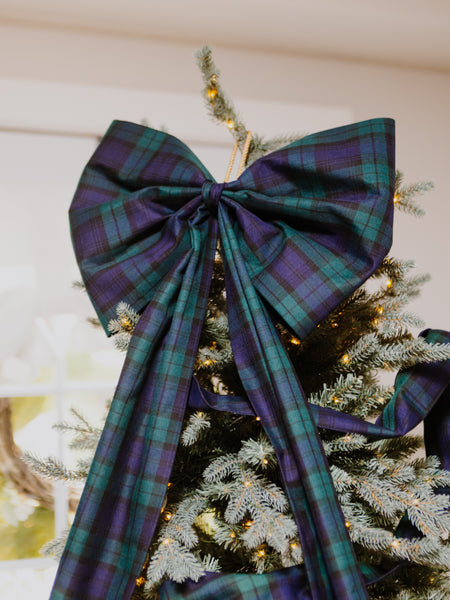close up of a Black Watch tartan Christmas tree over sized bow on the top of a Christmas tree.