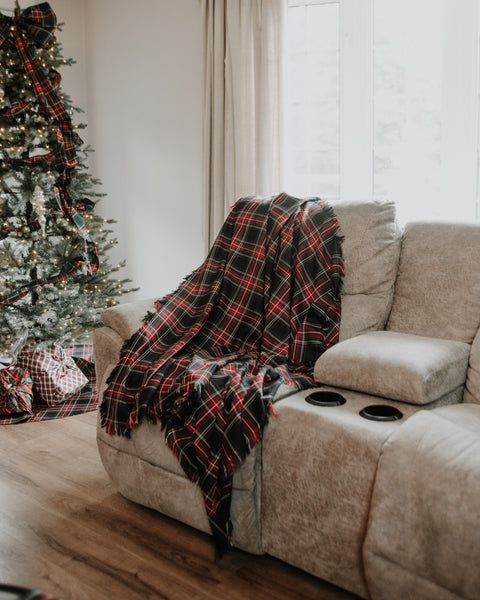 Black Stewart tartan throw on a couch with Christmas tree in the background.