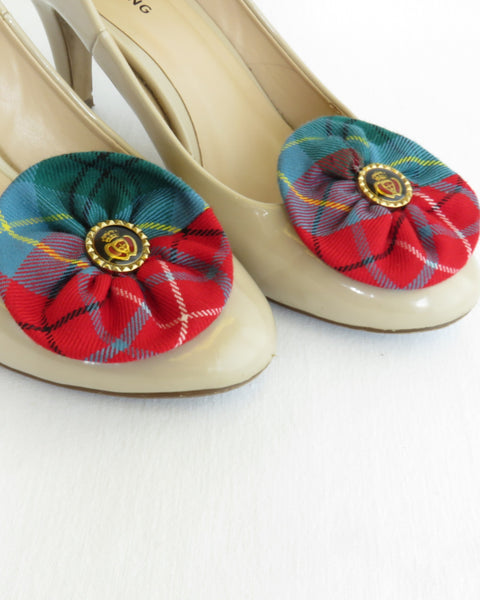 Beige high-heeled shoes with red and blue plaid flower shoe clips on a white background