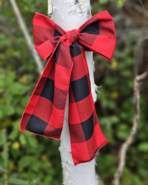 Red and black checkered bow tied to a white branch with a natural background