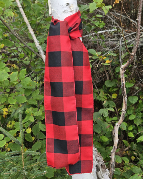 Red and black checkered scarf for Christmas decor draped over a tree branch with a natural background