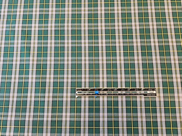 Green, gray and yellow plaid fabric with ruler to measure scale of the cape Breton tartan fabric