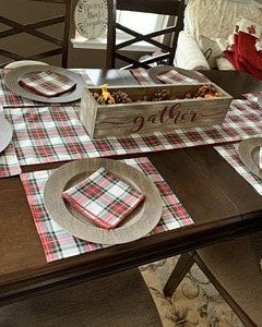 Dining table set with plaid placemats, napkins, and a decorative box on a checkered tablecloth, farmhouse style