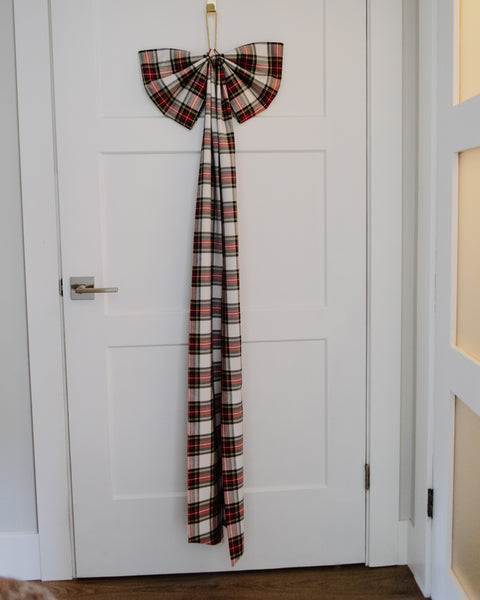over size dress stewart tartan white red green and gold plaid christmas tree bow on the front of a white door.