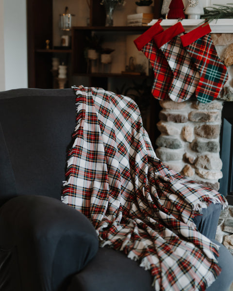 Dress Stewart tartan throw on a gray armchair with plaid stockings hung on a mantle in the background.