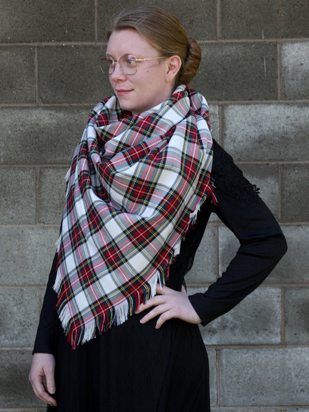 Woman wearing a white and red plaid scarf against a brick wall