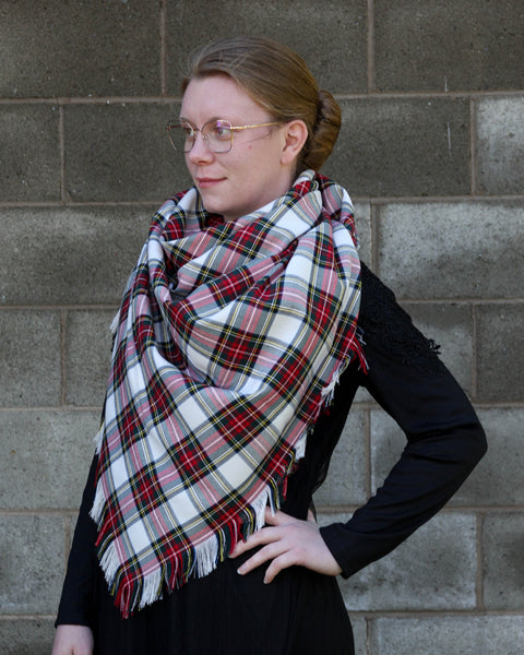 Person wearing a plaid scarf against a brick wall