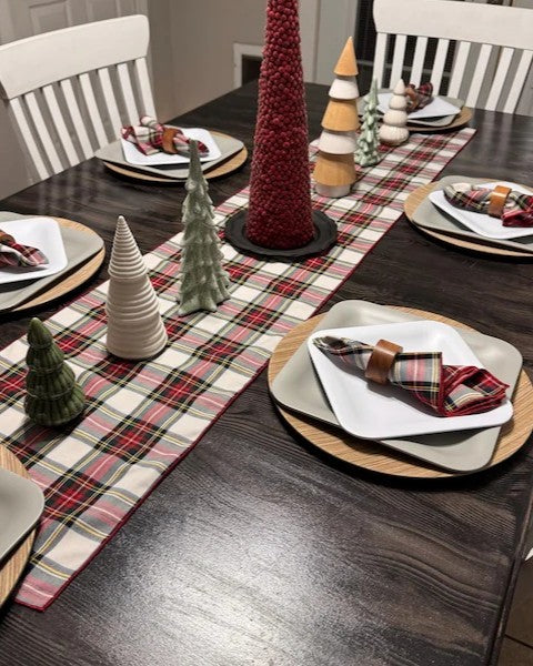 Dining table set with plaid table runner, Christmas decorations, and plaid napkins.