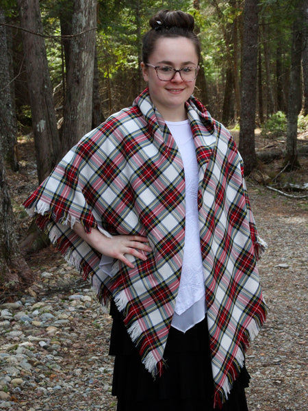 Person wearing a white and red Dress Stewat plaid shawl in a forest setting