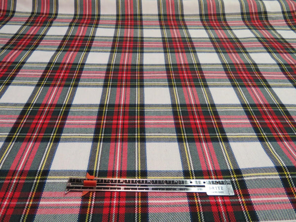 White and red plaid fabric laid flat with a ruler placed on top to show the repeat and scale of the tartan pattern.