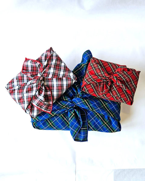 3 packages wrapped in plaid reusable gift wrap in royal blue plaid, Christmas plaid and Dress Stewart plaid