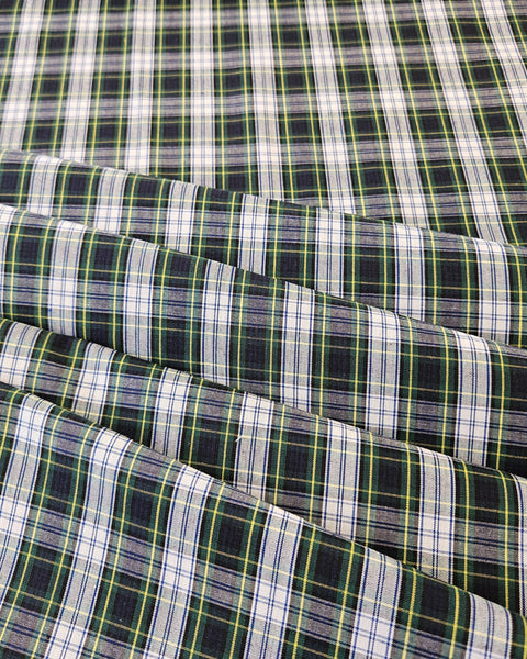 Close up of white, navy, green and yellow plaid cotton fabric folded in rows