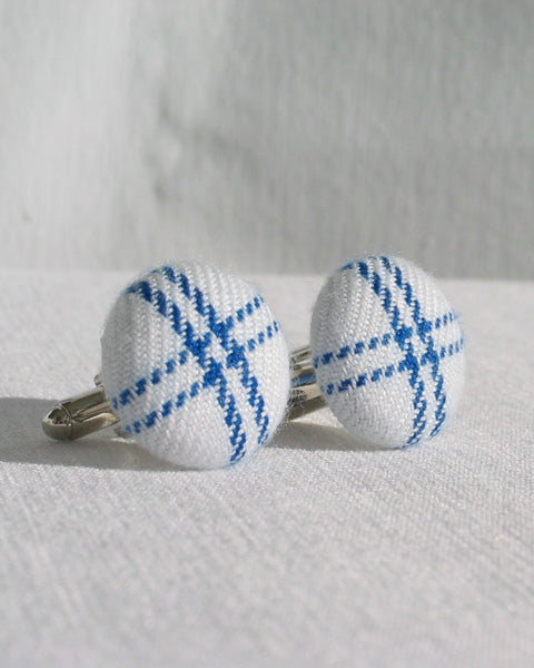 White and blue plaid cufflinks on a light gray background