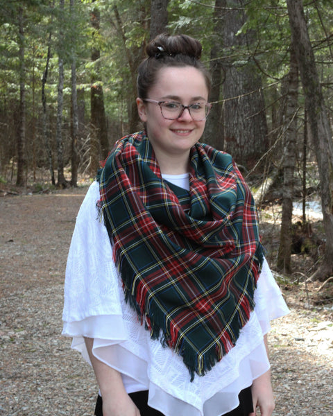 Person wearing a green and red plaid scarf in a forest setting