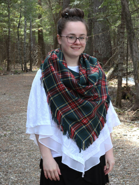 Person wearing a green plaid scarf in a forest setting