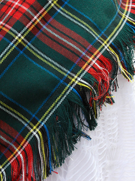 Close-up of a plaid scarf fringe of colorful threads on a textured white background
