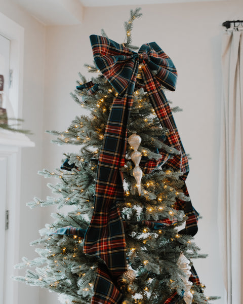close up of a green stewart tartan christmas tree bow on a prelit christmas tree
