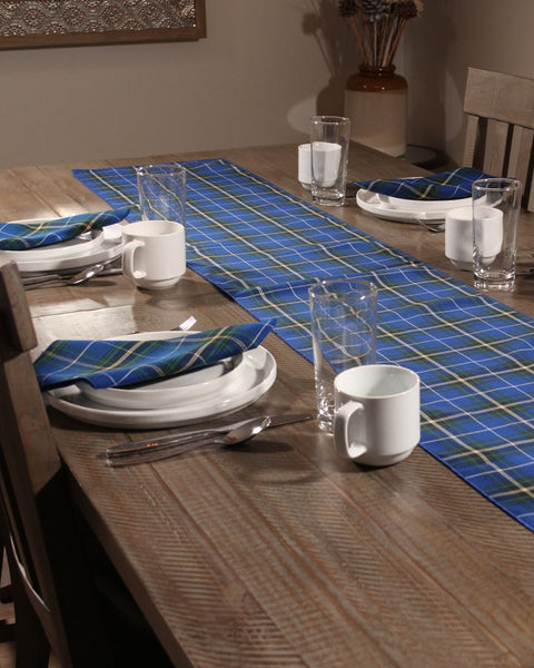 Nova Scotia tartan tablerunner with matching napkins on white plates silverware and cups set on a wooden table