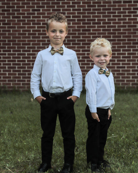 Two young boys in formal attire wearing Saskatchewan tartan bow ties standing in front of a brick wall.