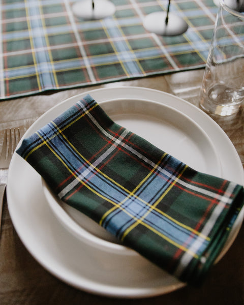 white plates topped with a green blue red yellow and white plaid napkin all sitting on a wooden table