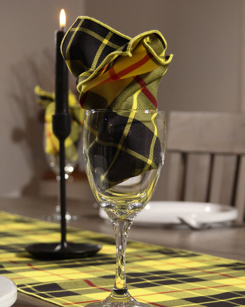 Wine glass with a yellow plaid napkin on a MacLeod tartan tablecloth, candle in the background 