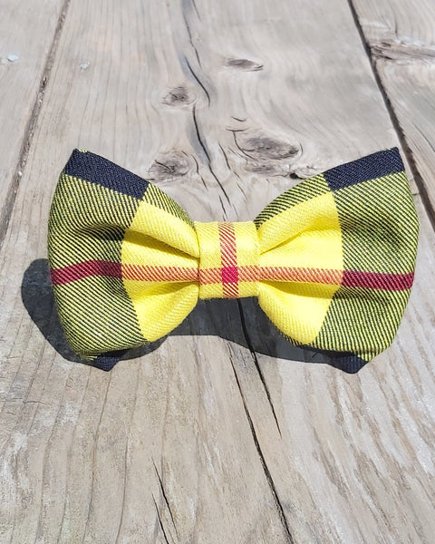 Bight yellow plaid pet bow tie in MacLeod tartan made by Taylors Tartans placed on a wooden surface