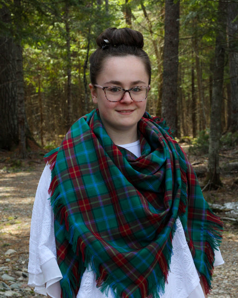 Person wearing a green and red Manitoba plaid scarf in a forest setting