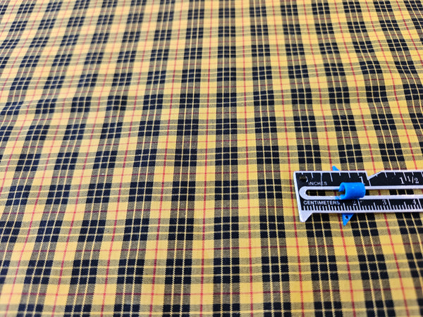 bright yellow, black and red plaid cotton fabric with silver and blackruler for size comparison