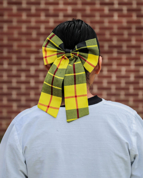 Girl wearing a large bright yellow and black plaid bow in their hair MacLeod of Lewis bow by Taylors Tartans