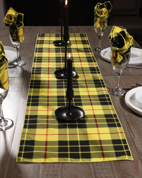 Yellow plaid table runner with black candle holders on a wooden table.