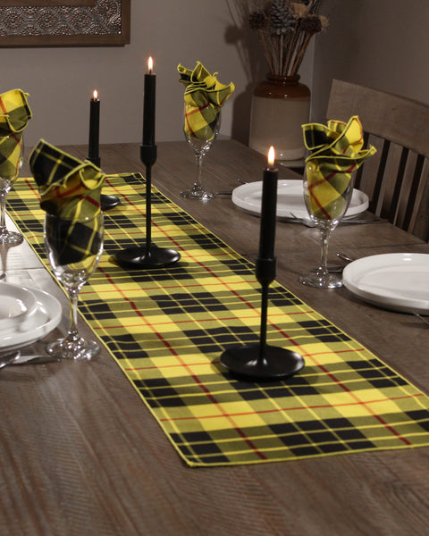 Dining table set with bright yellow and black plaid placemats, black candles, and plaid napkins.
