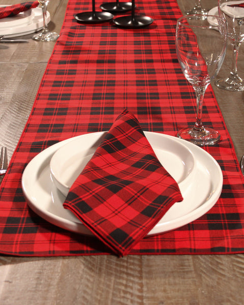 Red and black plaid table runner with white plates and napkins on a wooden table made by Taylors Tartans