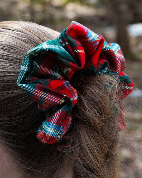 Red and green plaid scrunchie on a person's hair against a blurred natural background