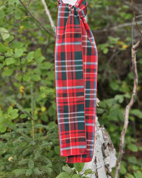 Red plaid New Brunswick tartan fabric draped over a branch with a natural background