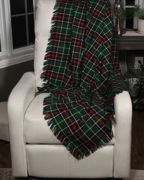 Newfoundland tartan green and red plaid blanket draped over a white chair in a cozy room.