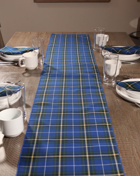 Dining table set with a Nova Scotia tartan plaid runner, plates, cups, and glasses.
