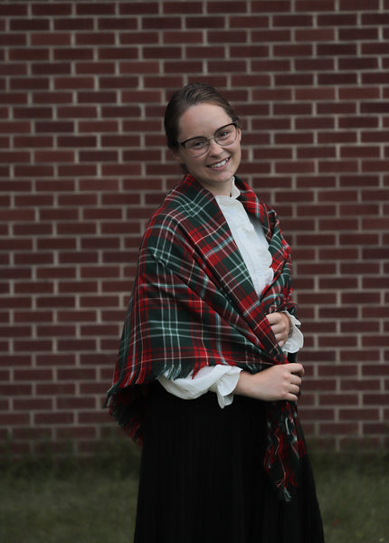 woman wearing a New Brunswick tartan plaid shawl in front of a brick wall