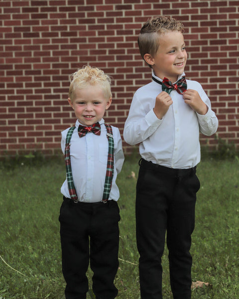 Smiling blond boy with older brother wearing white shirts, black pants, New Brunswick tartan bow ties and suspenders