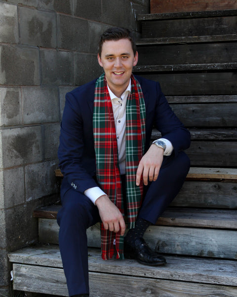 Man in a suit with a plaid scarf sitting on wooden steps.