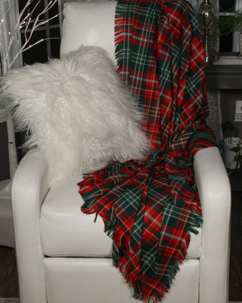 White chair with a fluffy white pillow and a red and green plaid blanket