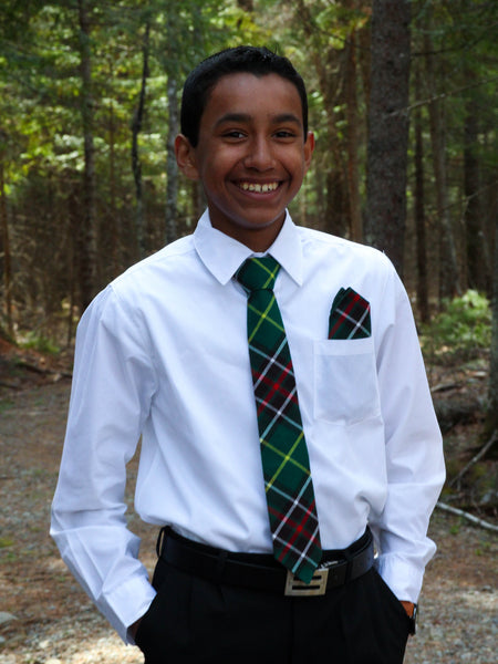 Person wearing a white shirt, green plaid tie, and black pants in a forest setting